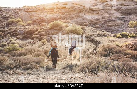 Junge Leute, die Pferde reiten, die einen Ausflug bei Sonnenuntergang machen - Wild Couple hat Spaß auf einer Reittour - Training, Kultur, Leidenschaft, gesunder Lebensstil, spo Stockfoto