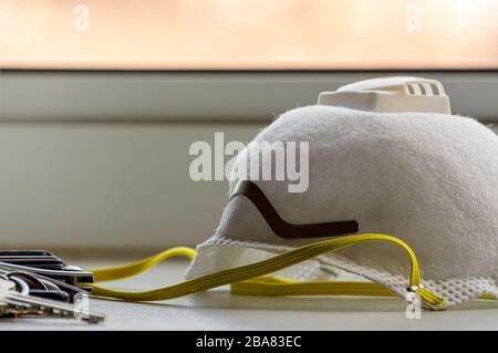 N95 Atemschutzmaske mit Tasten und Brieftasche auf einem Tresen zu Hause. Persönliche Schutzausrüstung. Stockfoto