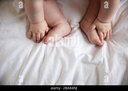 Nahaufnahme eines Babys Hände und Füße auf einem weißen Betttuch Stockfoto