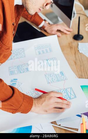 Zugeschnittene Ansicht des Designers, der mit Vorlagen für das Benutzererlebnis auf dem Tisch arbeitet Stockfoto