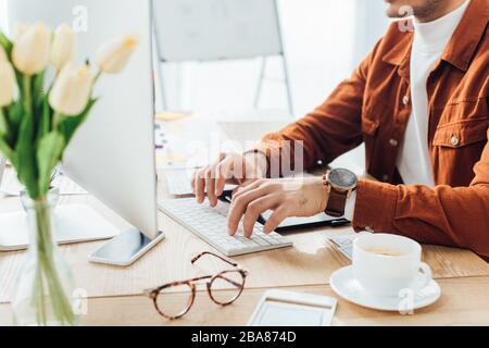 Zugeschnittene Ansicht des Entwicklers mit Computer in der Nähe von Vorlagen für ux-Design und Kaffee auf dem Tisch Stockfoto