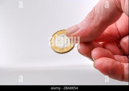 Britische Pfund Münzkrone Seite in menschlicher Hand für Zahlung auf weißem Hintergrund mit Kopierraum Stockfoto