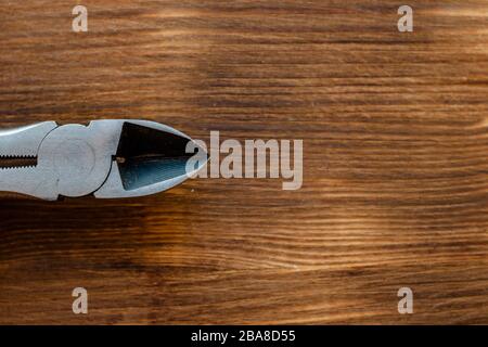 Alte Werkzeugzange auf braunem Holzhintergrund. Konzept des Arbeitstages Stockfoto