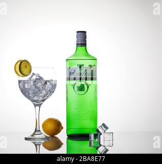 Gin Tonic Cocktail mit Flasche Gin, limon und Limonscheiben und Eis auf Spiegelkulisse mit Kopierraum Stockfoto