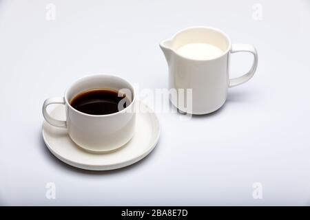 Creamer und Tasse Kaffee auf weißem Hintergrund Stockfoto