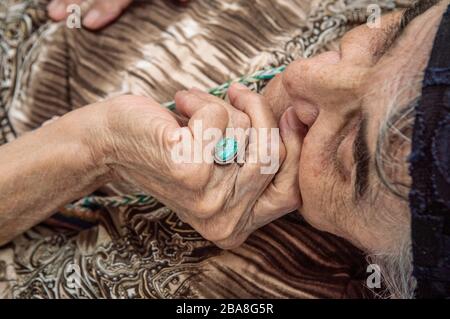 Gesicht einer älteren türkischen Frau mit traditioneller Motorhaube. Nahaufnahme der Hand, die das Gesicht berührt. Stockfoto