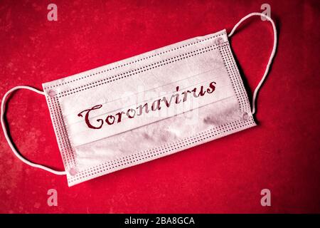 Roman Coronavirus - 2019-nCoV, WUHAN Virus-Konzept. Schutzmaske für chirurgische Eingriffe mit CORONAVIRUS-TEXT. Ausbruch des chinesischen Coronavirus. Roter Hintergrund. Stockfoto