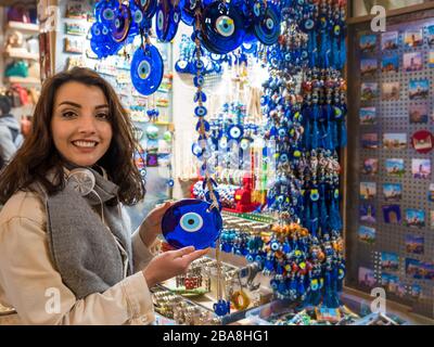 Schöne Frau zeigt blaue böse Augenperlen, die in Eminonu, Istanbul, Türkei, einen Laden in Egypt Bazaar verkauft haben Stockfoto