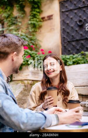 Selektive Fokussierung eines Paares mit Kaffeetassen, die sich im Café der Stadt gegenseitig betrachten Stockfoto