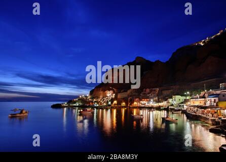 Nachtansicht von Ammoudi, einer der 2 kleinen Häfen von Oia und Oia selbst auf dem oberen Teil des Fotos. Santorin, Griechenland Stockfoto