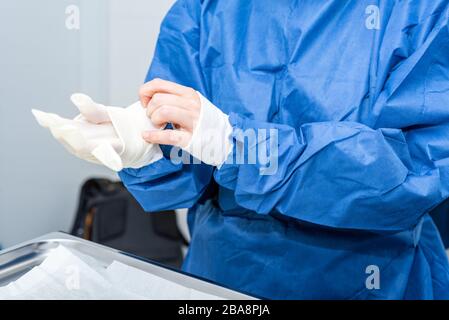 Covid-19. Der Arzt legt Schutzhandschuhe an. Persönliche Schutzausrüstung im Kampf gegen die Coronavirus Krankheit . Stockfoto