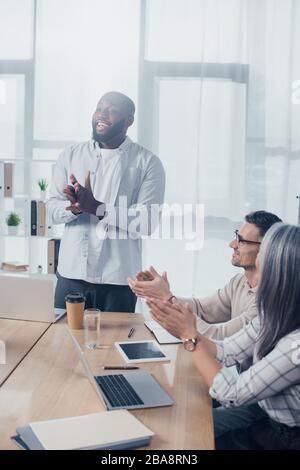 Lächelnde multikulturelle Kollegen klatschen während des Treffens in der Kreativagentur Stockfoto