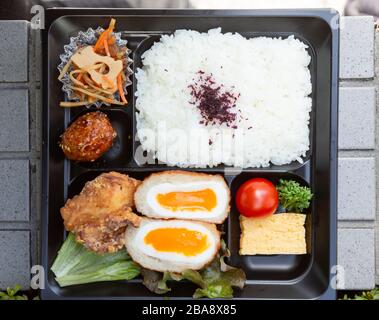 Kaufhaus bento mit Reis, eingelegtem Gemüse, Omelette, Tomate, Ei, gebratenem Huhn und Fleischball. Stockfoto