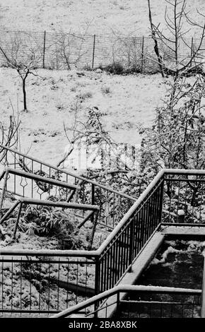 Schnee auf dem Geländer eines Hauses und im kleinen Garten. Spiel der Linien und Kontraste des Lichts Stockfoto
