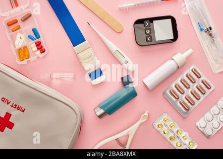 Draufsicht über Erste-Hilfe-Kit, Pillen und medizinische Gegenstände auf pinkfarbenem Hintergrund Stockfoto