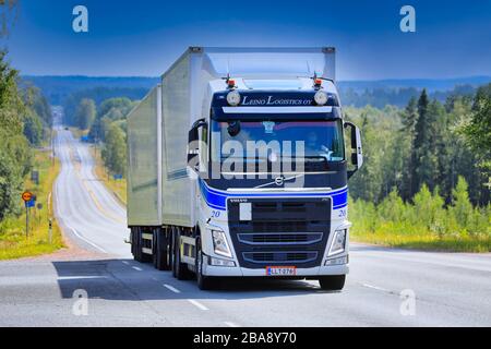 Weißer Volvo FH Truck Leino Logistics Oy zieht im Sommer Anhänger auf der malerischen Autobahn unter blauem Himmel. Ikaalinen, Finnland. August 2019. Stockfoto