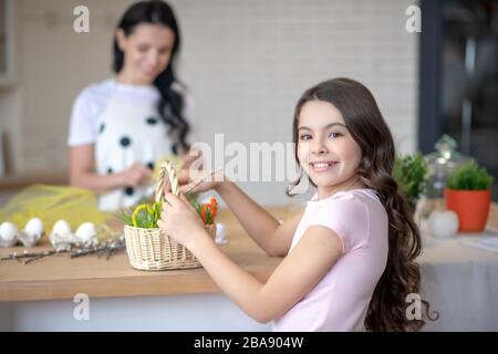 Ziemlich langhaarige Mädchen, die den osterkorb in ihren Händen halten Stockfoto