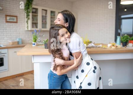 Brünette Frau und ihre süße Tochter umarmen sich Stockfoto