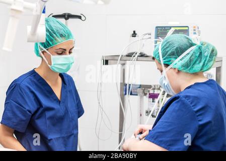 Covid-19-Ausbruch. Mitarbeiter im Gesundheitswesen. Krankenschwester, die auf einer Intensivstation arbeitet. Mechanische Belüftungsanlage im Hintergrund . Stockfoto