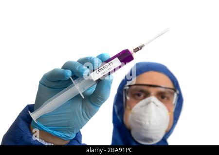 Arzt in Schutzmaske und Handschuhen mit Spritze mit Virus COVID 19 Impfstoff. Stockfoto