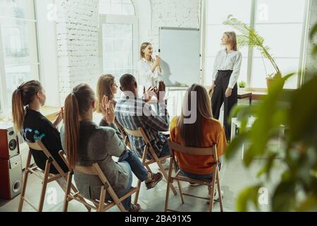 Stellen einer Frage. Referentin, die in der Halle in der Werkstatt vorspricht. Business Center. Rückansicht der Teilnehmer im Publikum. Konferenzveranstaltung, Schulung. Bildung, Vielfalt, integratives Konzept. Stockfoto