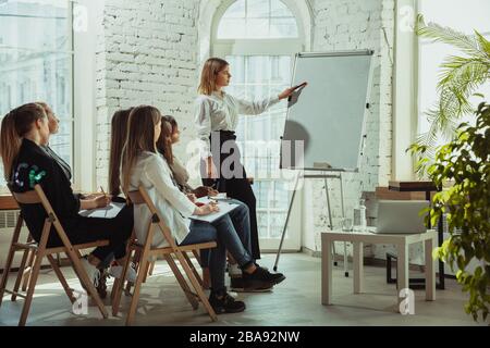 Lektion. Referentin, die in der Halle in der Werkstatt vorspricht. Business Center. Seitenansicht der Teilnehmer im Publikum. Konferenzveranstaltung, Schulung. Bildung, Vielfalt, integratives Konzept. Stockfoto