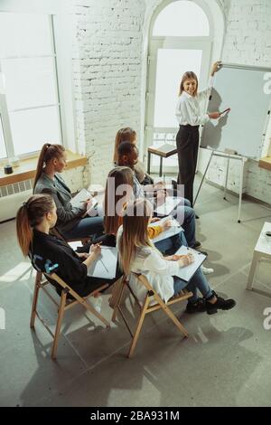 Erweitert. Referentin, die in der Halle in der Werkstatt vorspricht. Business Center. Ein hoher Blickwinkel auf die Teilnehmer im Publikum. Konferenzveranstaltung, Schulung. Bildung, Vielfalt, integratives Konzept. Stockfoto