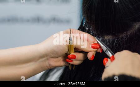 Professionelle Frau, die Haarverlängerungen mit verschiedenen Griffarten anwendet. Nano-Ringe-Verlängerungen aus echten Humas-Haaren. Stockfoto