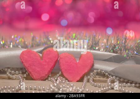 Herzförmige Plätzchen für den Valentinstag auf abstraktem unscharfen Bokeh-Hintergrund. Valentinskekse auf Holztisch Stockfoto