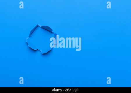 Blauer Hintergrund mit Loch im Papier. Kopierbereich Stockfoto