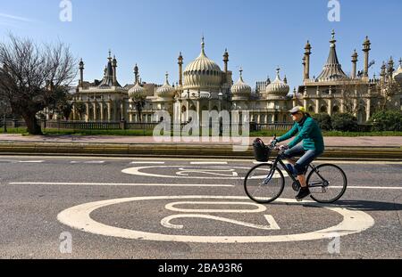 Brighton UK 26. März 2020 - EIN Radfahrer fährt am Royal Pavilion in Brighton vorbei, da Straßen am dritten Tag extrem ruhig sind. Die Einschränkungen für die Sperrung der Regierungen während der Coronavirus COVID-19-Pandemie-Krise. Kredit: Simon Dack / Alamy Live News Stockfoto