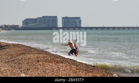 Brighton UK 26. März 2020 - Schwimmer genießen ein Bad im Meer vor Brighton Strand am Tag drei der Regierungen Sperrbeschränkungen während der Coronavirus COVID-19-Pandemie-Krise. Kredit: Simon Dack / Alamy Live News Stockfoto