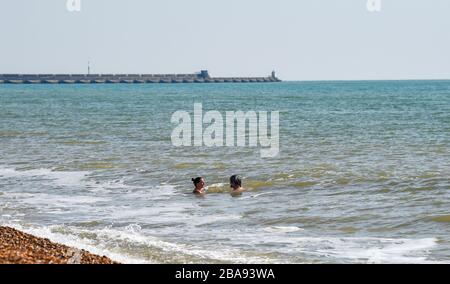 Brighton UK 26. März 2020 - Schwimmer genießen ein Bad im Meer vor Brighton Strand am Tag drei der Regierungen Sperrbeschränkungen während der Coronavirus COVID-19-Pandemie-Krise. Kredit: Simon Dack / Alamy Live News Stockfoto