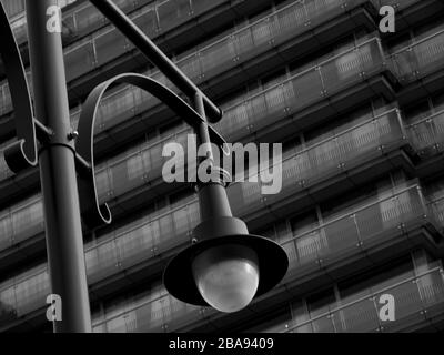 Blick auf alte Straßenlampen im Vintage-Stil auf hautengen hohen Stahlpfosten und große Glaslinsenverkleidungen und elegante Außenkorridore aus Glas im Hotelgebäude Stockfoto