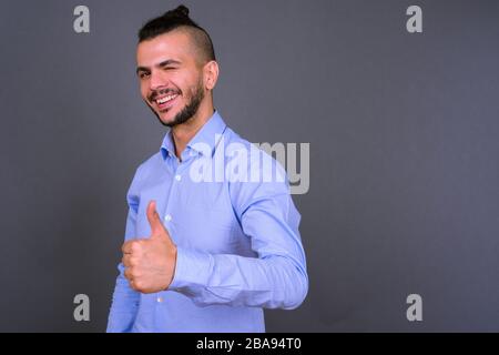 Porträt eines glücklichen, gutaussehenden, bärtigen türkischen Geschäftsmannes, der mit den Daumen nach oben drückt Stockfoto