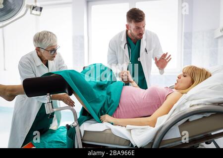 In dem Krankenhaus treibt die Frau in der Arbeit die Geburt voran, Geburtshelfer helfen Stockfoto