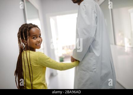 Kinderarzt hält jungen Mädchen die Hand im Krankenhaus Stockfoto