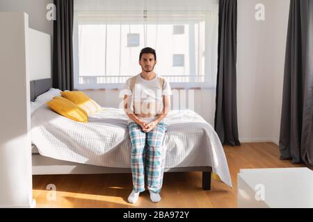 Junger Mann, der einen Rückenband trägt. Lendenwirbelstütze, Rückenstütze für Rückentrauma oder Muskelrückenstamm. Stockfoto