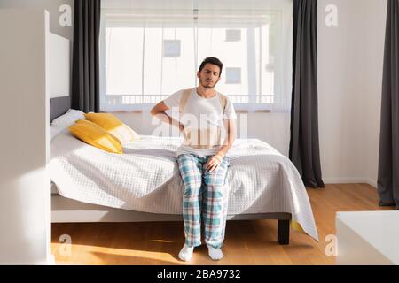 Junger Mann, der einen Rückenband trägt. Lendenwirbelstütze, Rückenstütze für Rückentrauma oder Muskelrückenstamm. Stockfoto