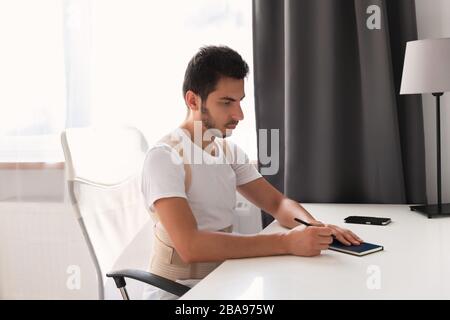 Junger Mann, der einen Rückenband trägt. Lendenwirbelstütze, Rückenstütze für Rückentrauma oder Muskelrückenstamm. Stockfoto