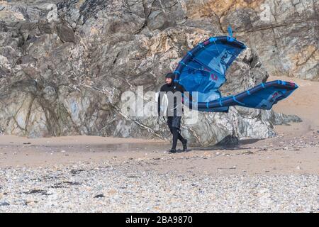 Ein Kite-Boarder, der seine Ausrüstung zum Kite-Boarding im Surfing bei starkem Wind am Fistral Beach in Newquay in Cornwall trägt. Stockfoto