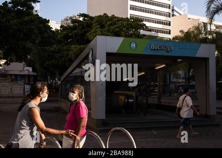 Rio De Janeiro, Brasilien. März 2020. Zwei Frauen tragen Gesichtsmasken vor der Botafogo U-Bahn-Station. Innerhalb einer Woche ist Rio de Janeiro weitgehend isoliert, Schulen und Geschäfte geschlossen, der Verkehr an Land und in der Luft abgeschnitten, und die Bewohner drängten sich, zu Hause zu bleiben. Kredit: Pedro Prado / dpa / Alamy Live News Stockfoto