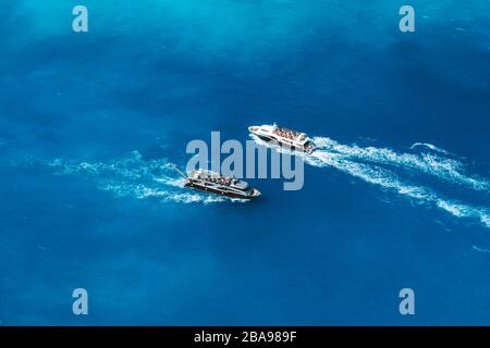 Voll besetzte Touristenboote im offenen Meer auf dem Weg zum weltberühmten Navagio Beach auf der Insel Zakynthos in Griechenland. Stockfoto