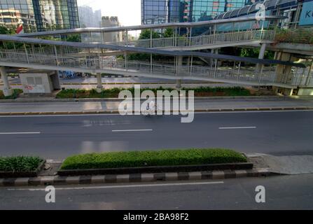 Eine Mutter und ihre Tochter fahren mit dem Fahrrad auf einer leeren Straße in Jakarta, Indonesien. Stockfoto