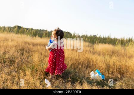 Kleines Mädchen sammelt im Wald verstreuten Müll. Kleines Mädchen sammelt im Wald verstreuten Müll. Das Kind kämpft für eine saubere Umwelt. Stockfoto