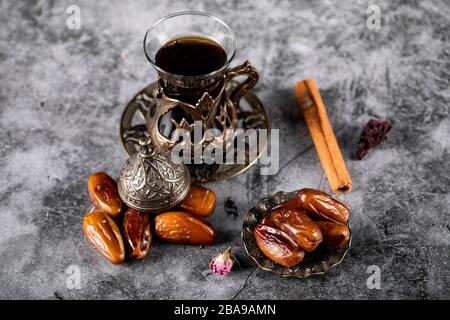 Orientalische Datteln in einer Untertasse im ethnischen Stil mit einem Glas Tee und Zimtstäbchen. Draufsicht Stockfoto