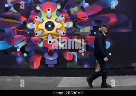 Ein Mann geht an einem neuen Wandbild in Dublin vorbei, das von einer Untergruppe der Kunstgruppe inspiriert ist, die von den Informationen in einem schriftlichen Stück auf ihrer Website mit dem Titel CORONAVIRUS: The Virus Era inspiriert ist. Stockfoto