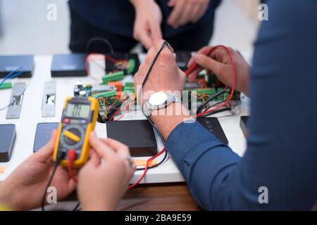 Zwei junge schöne Ingenieuren, die bei Elektronik komponenten. Tech Tests elektronische Anlagen in Service Center. Technologisch fortschrittliche wissenschaftliche Stockfoto