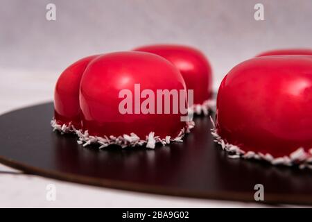 Nahaufnahme von Mousse-Kuchen mit roter Spiegelglasur. Französisches Dessert wird zubereitet. Gefrorenes Spiegel-Icing auf dem Kuchen. Backen- und Süßwarenkonzept. Stockfoto