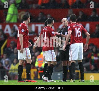 Schiedsrichter Mike Dean (rechts 2) wird von Spielern von Manchester United umzingelt, nachdem er das von Jonny Evans von Manchester United erzielte Eigentor vergibt Stockfoto